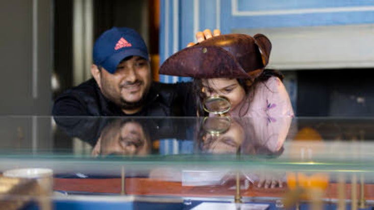 Family looking at a display case using a magnifying glass
